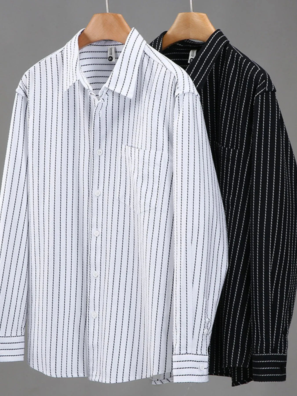 White and black striped button-up long-sleeve shirts on hangers