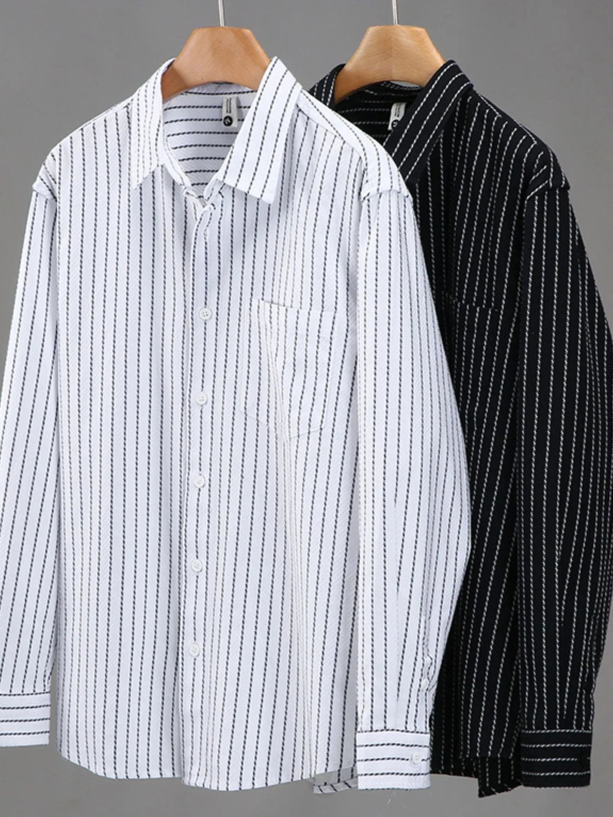White and black striped button-up long-sleeve shirts on hangers