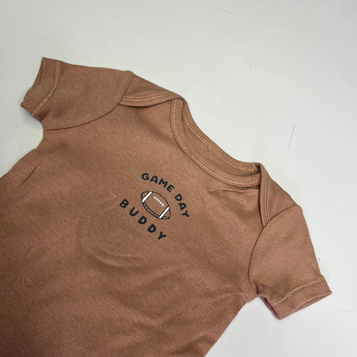 Brown short-sleeve bodysuit with “Game Day Buddy” logo on the chest.
