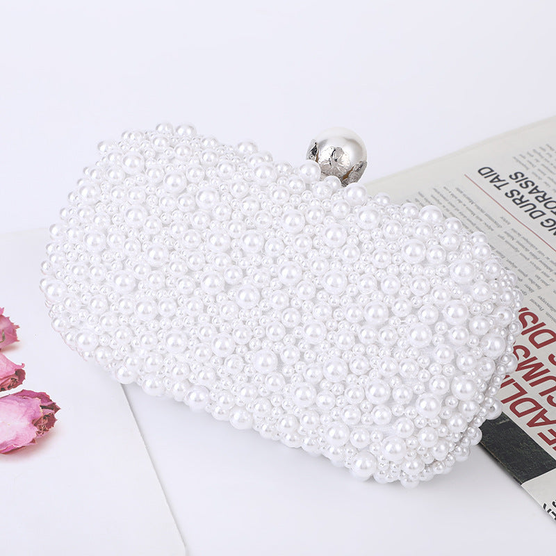 White pearl beaded clutch with round metal clasp, close-up side view