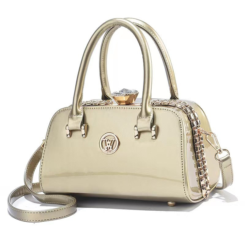 Gold patent leather handbag with top handles, chain strap, and front logo emblem