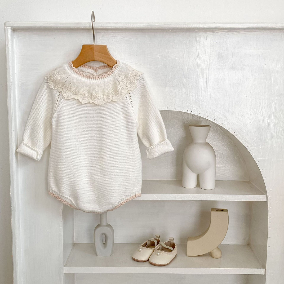 Off-white long-sleeve baby romper with raised lace collar and ribbed knit cuffs