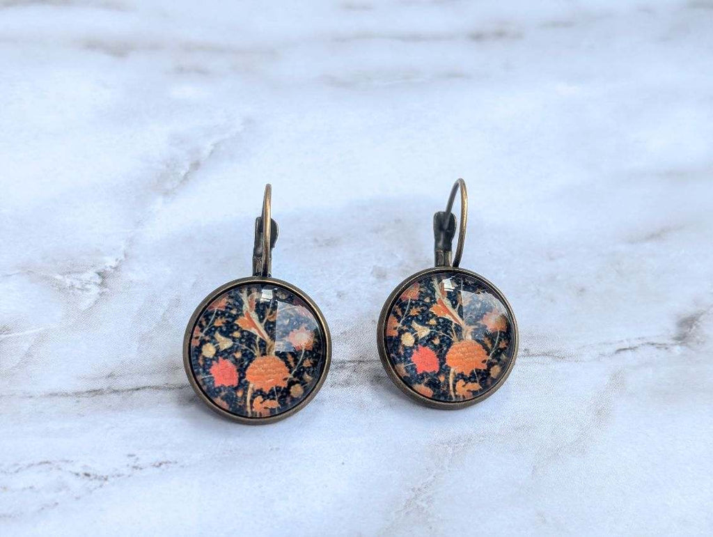 Round floral leverback earrings with orange and blue botanical print on dark background.