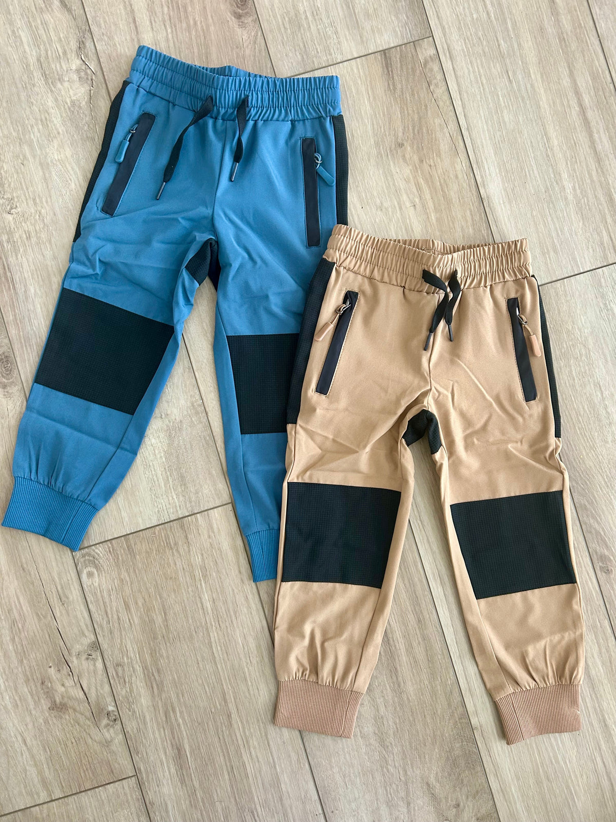 Kids hiking pants in tan and blue with black knee panels, elastic waist