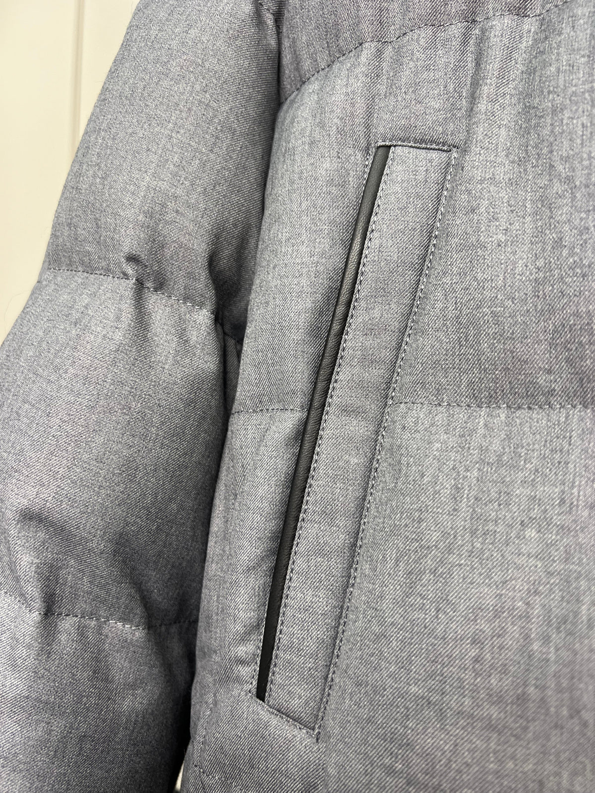 Grey padded coat arm with stitched utility-style pocket and seam lines