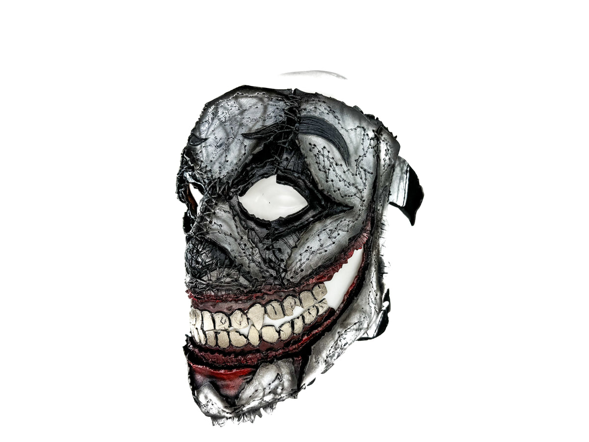 Full-face leather clown-style mask with hollow eye openings, gray texture, red trim, teeth