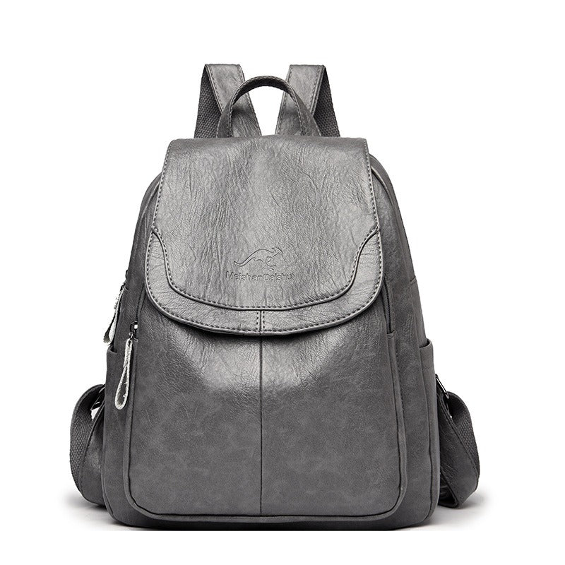 Women’s gray backpack with front flap pocket, top handle, and side zipper details