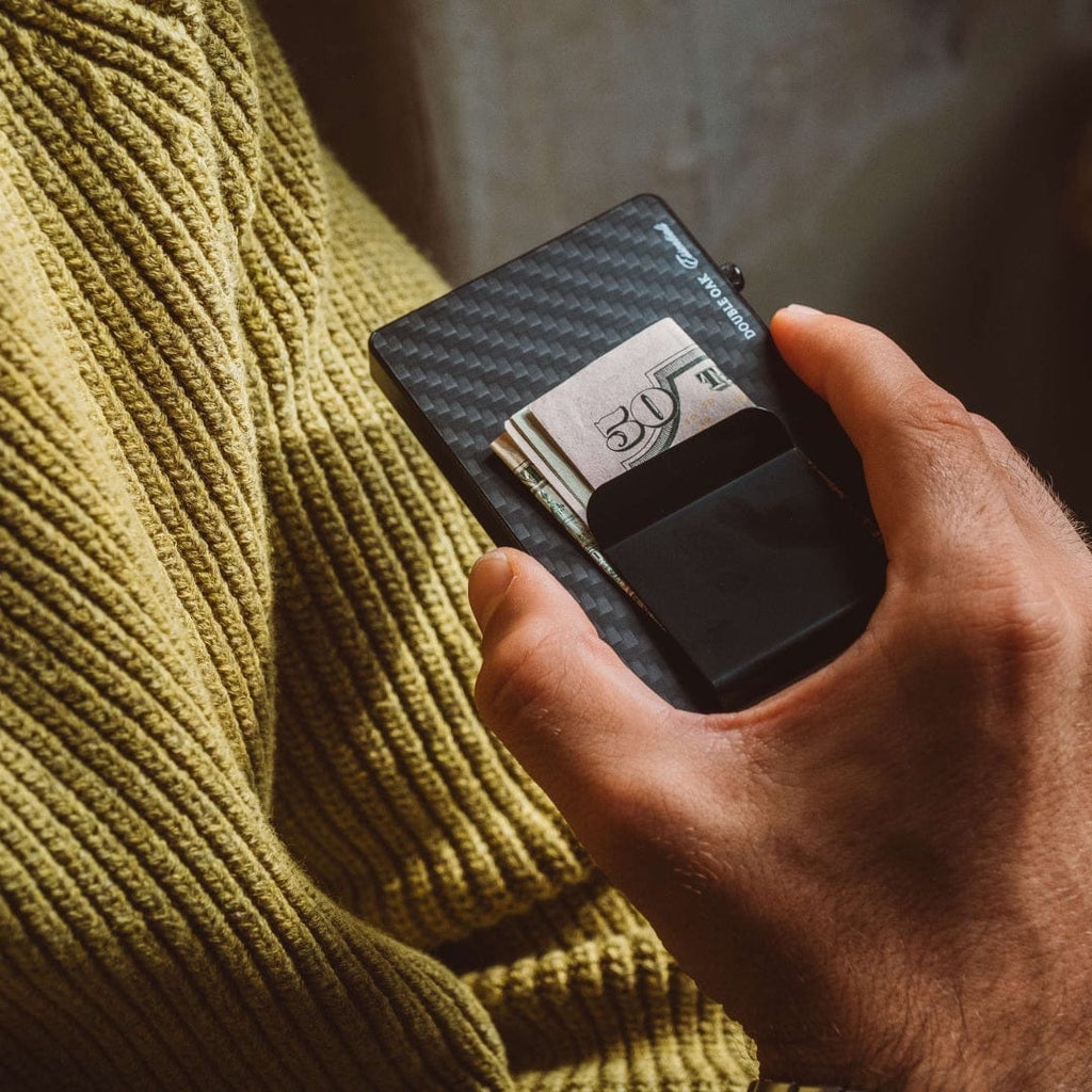 Carbon-fiber style dark cardholder with a 30€ bill slot and pop-up grip