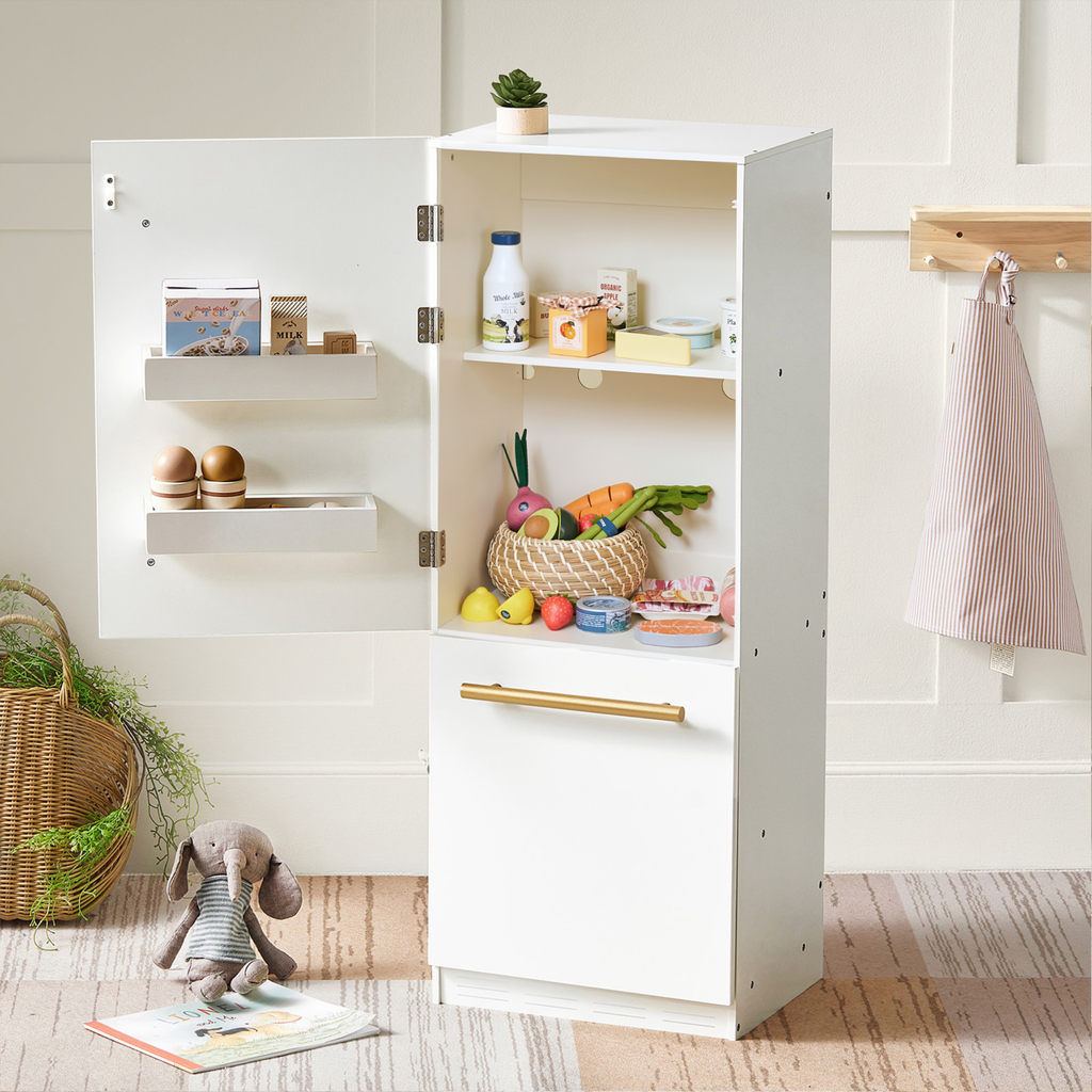 White play kitchen cabinet open with shelves stocked with toy organic fruit and veggies