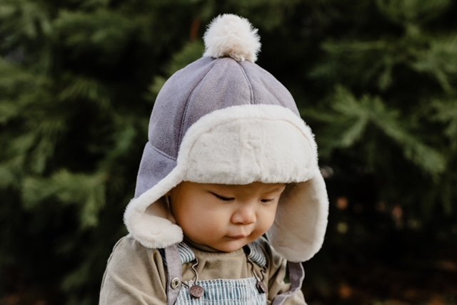 Gray kids winter trapper hat with white sherpa lining and fluffy top pom-pom