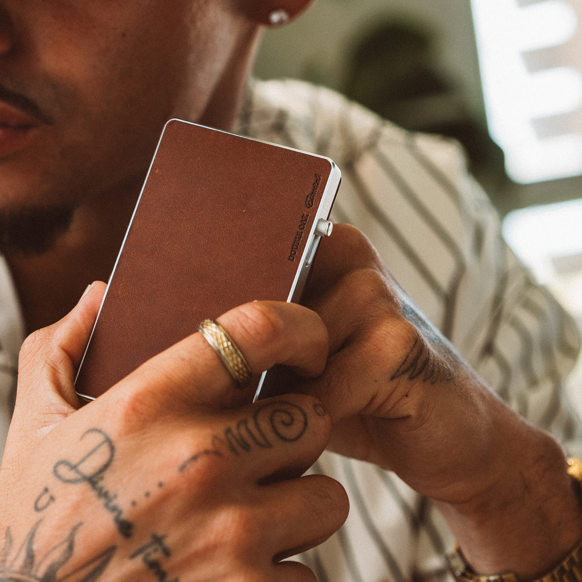 Brown leather cardholder wallet with metal frame and snap latch, held up for view