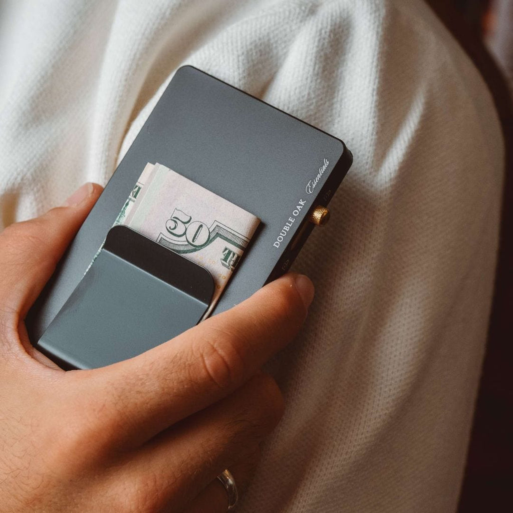 Dark gray pop-up cardholder open with 50 bill showing and brass button closure.