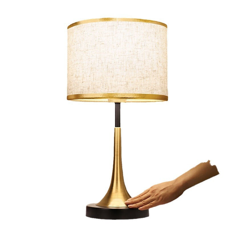 Gold standing table lamp with off-white fabric shade and dark base