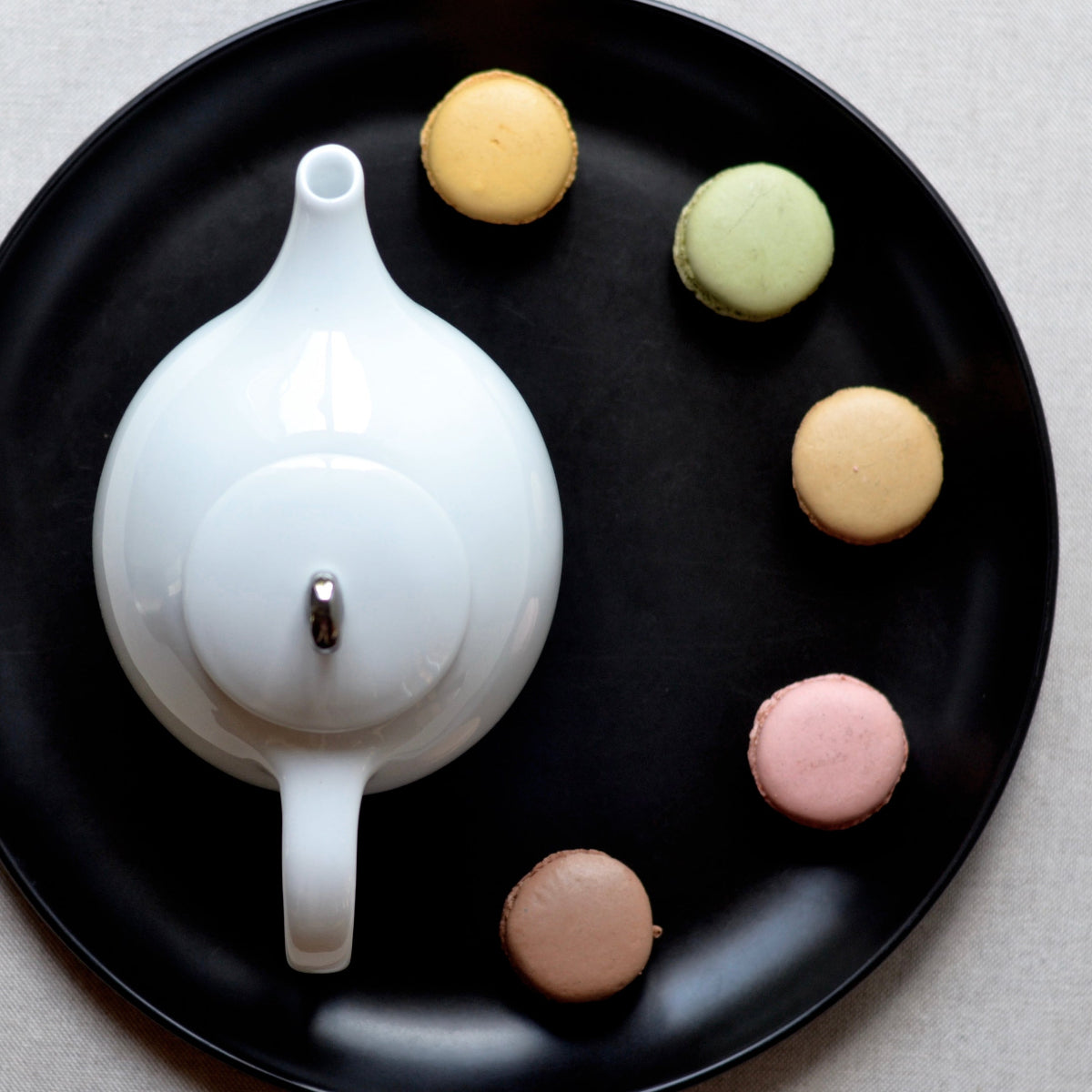 White ceramic teapot with infuser base and round lid, seen from above