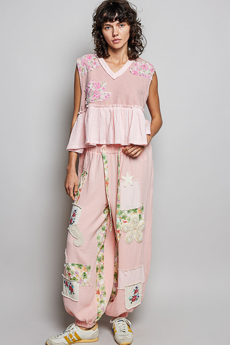 Pink sleeveless V-neck top with floral patch accents and layered ruffled peplum tiers