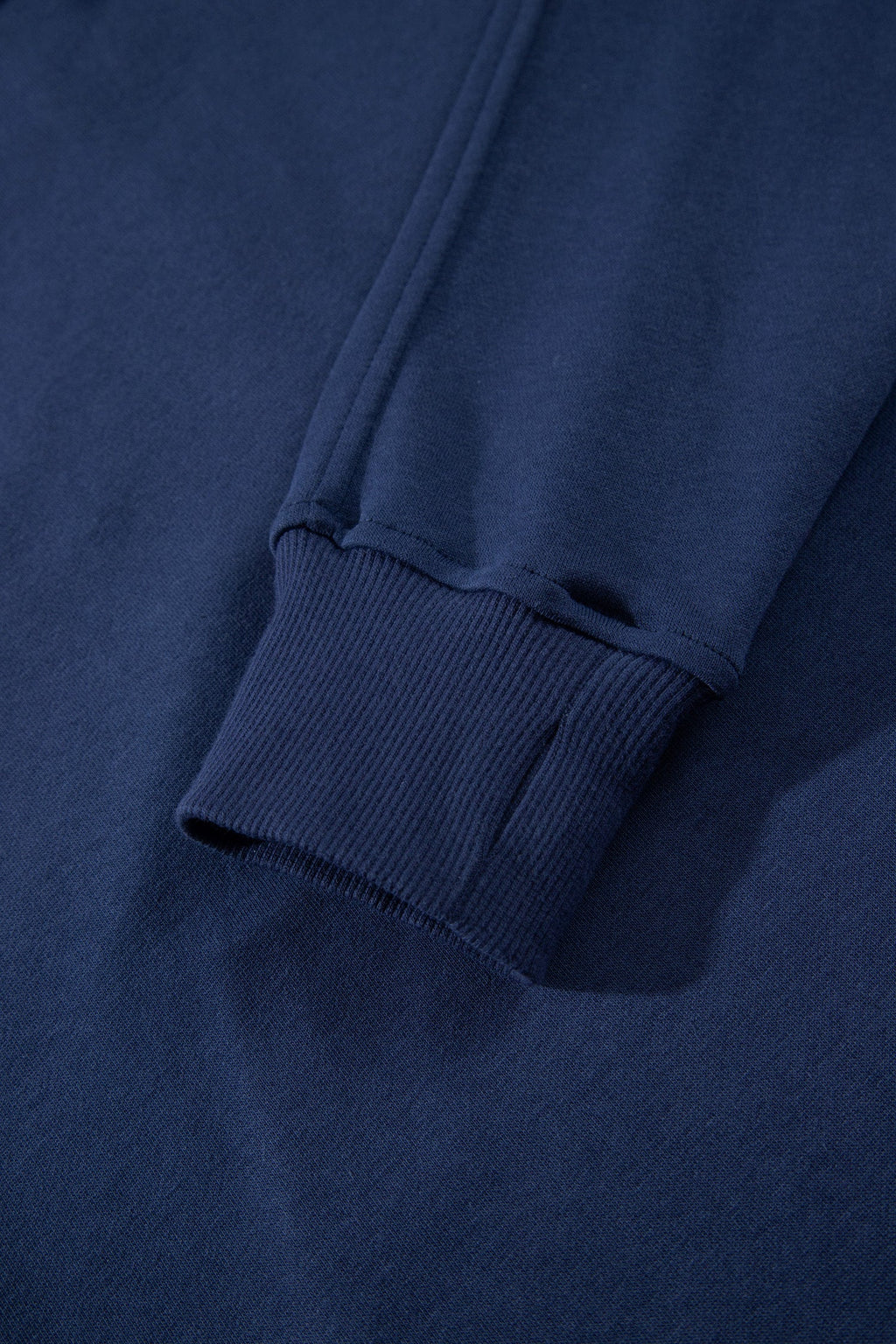 Navy ribbed cuff trim at sleeve hem on the zip-up top