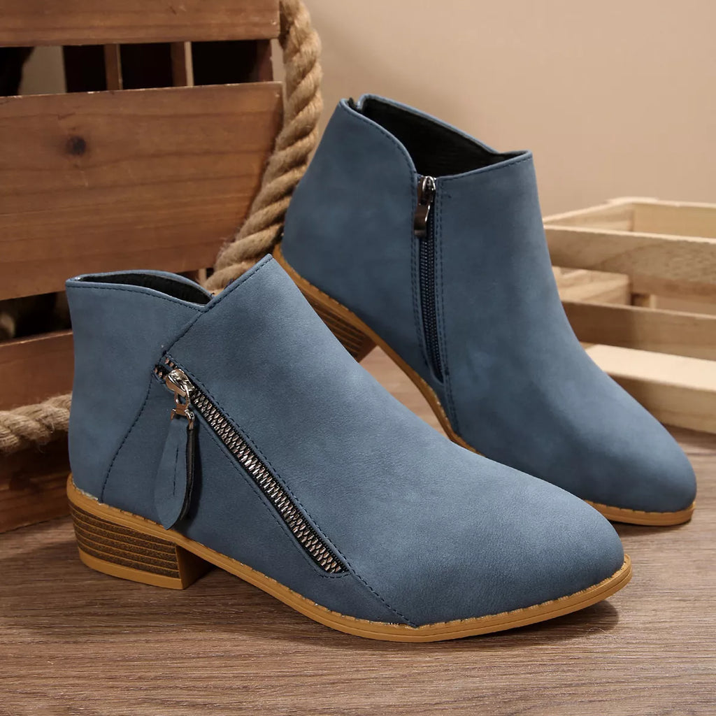 Dusty blue mid-height ankle boots with side zipper and block heel on tan outsole