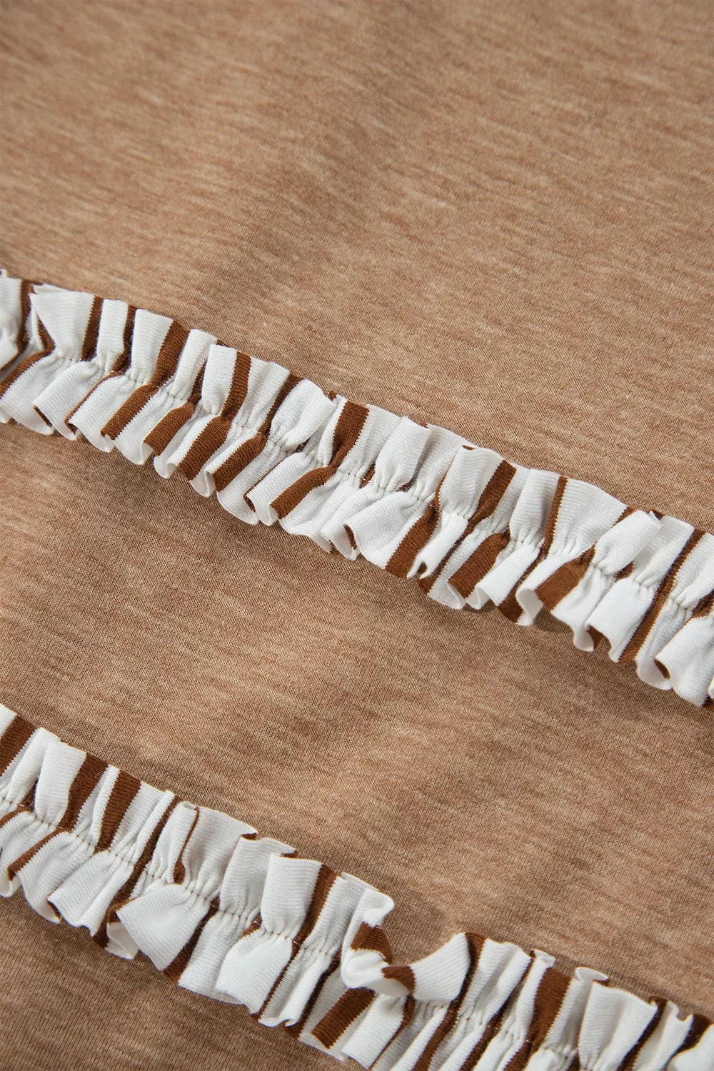 Close-up of camel pants hem with white ruffled trim and gathered texture