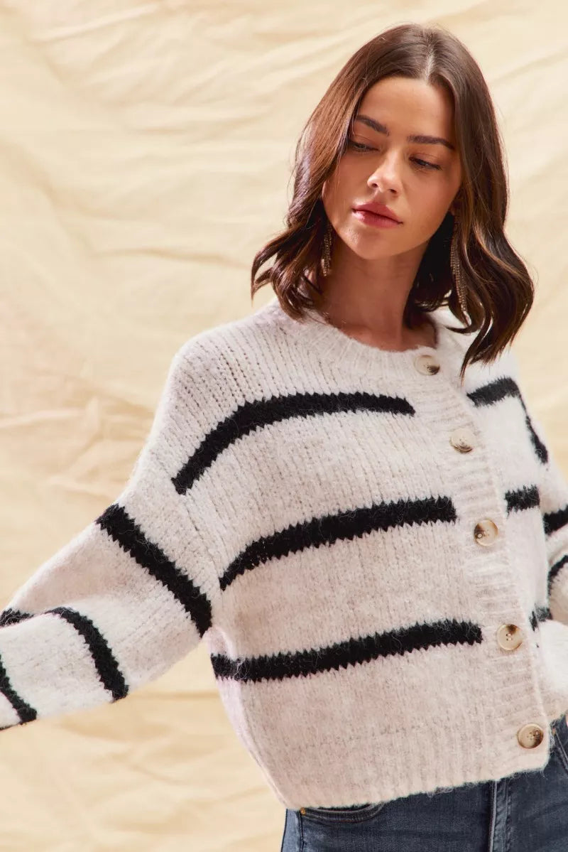Close view of button-front cream sweater with bold black stripe bands on sleeves