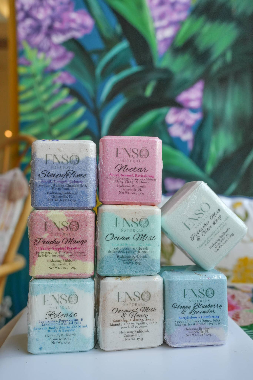 Stacked ENSO bath bomb boxes showing square cubes in purple, pink, blue, green, and white