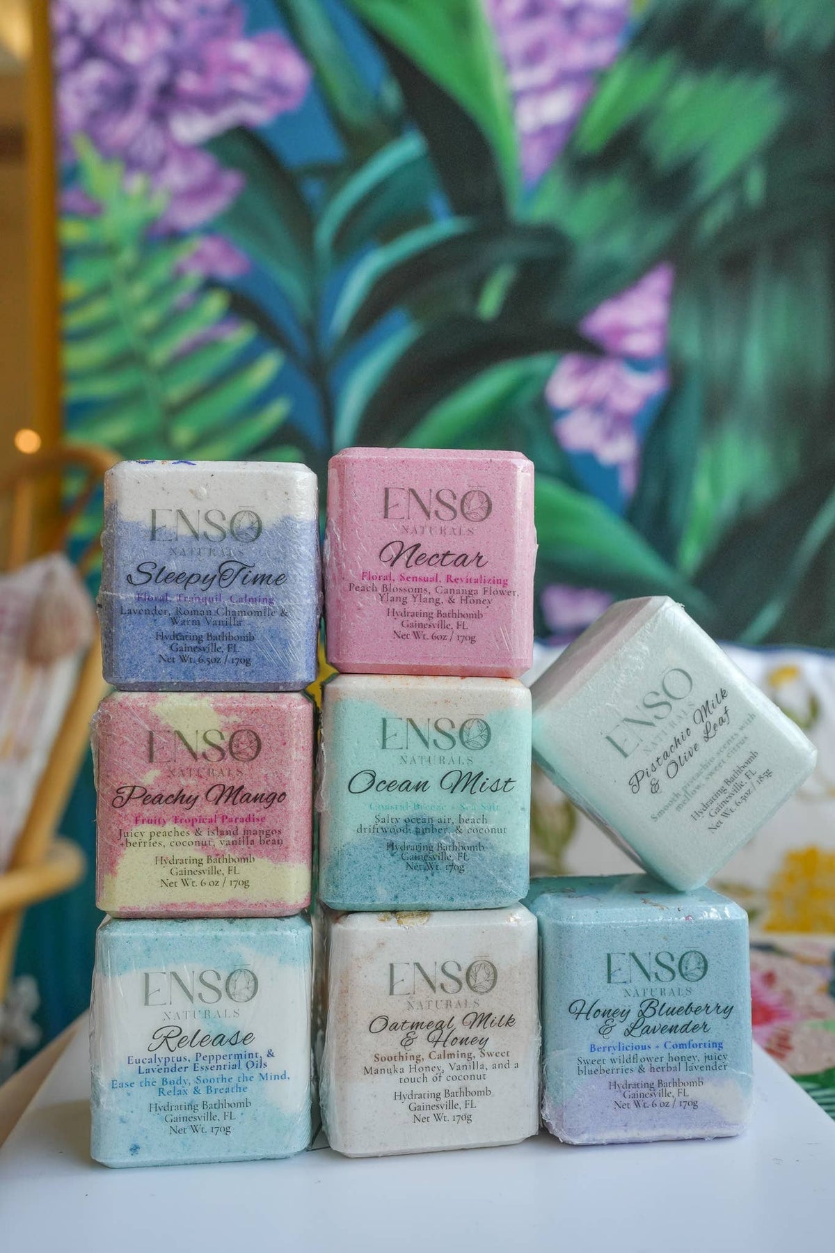 Stacked ENSO bath bomb boxes showing square cubes in purple, pink, blue, green, and white