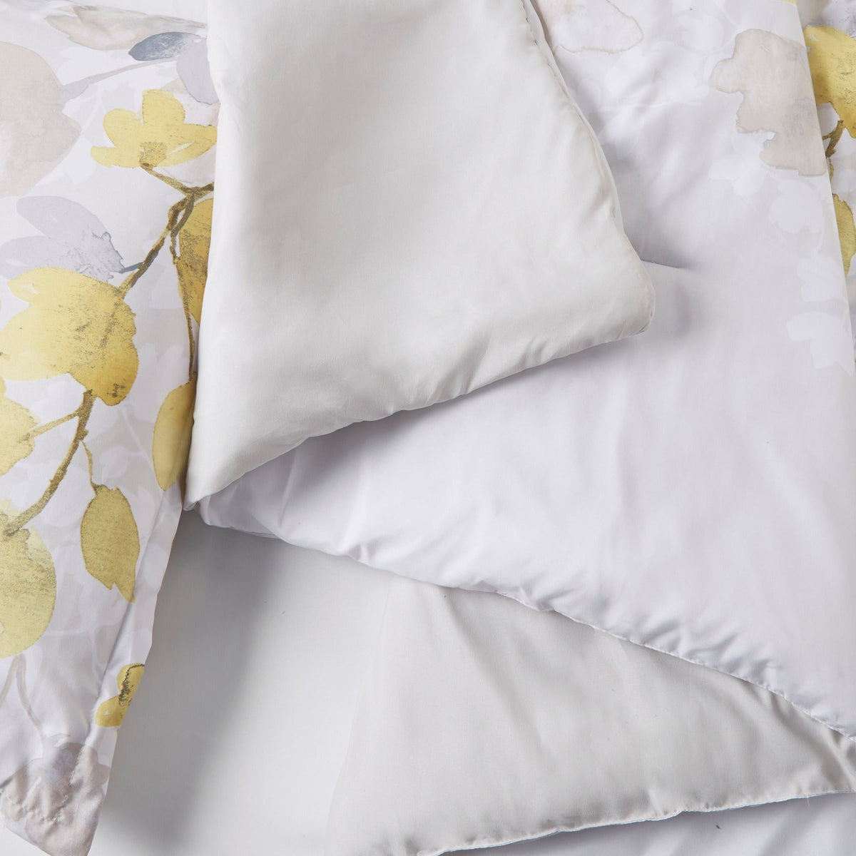 Close-up of Twin XL comforter and white pillow with multicolor yellow floral accents