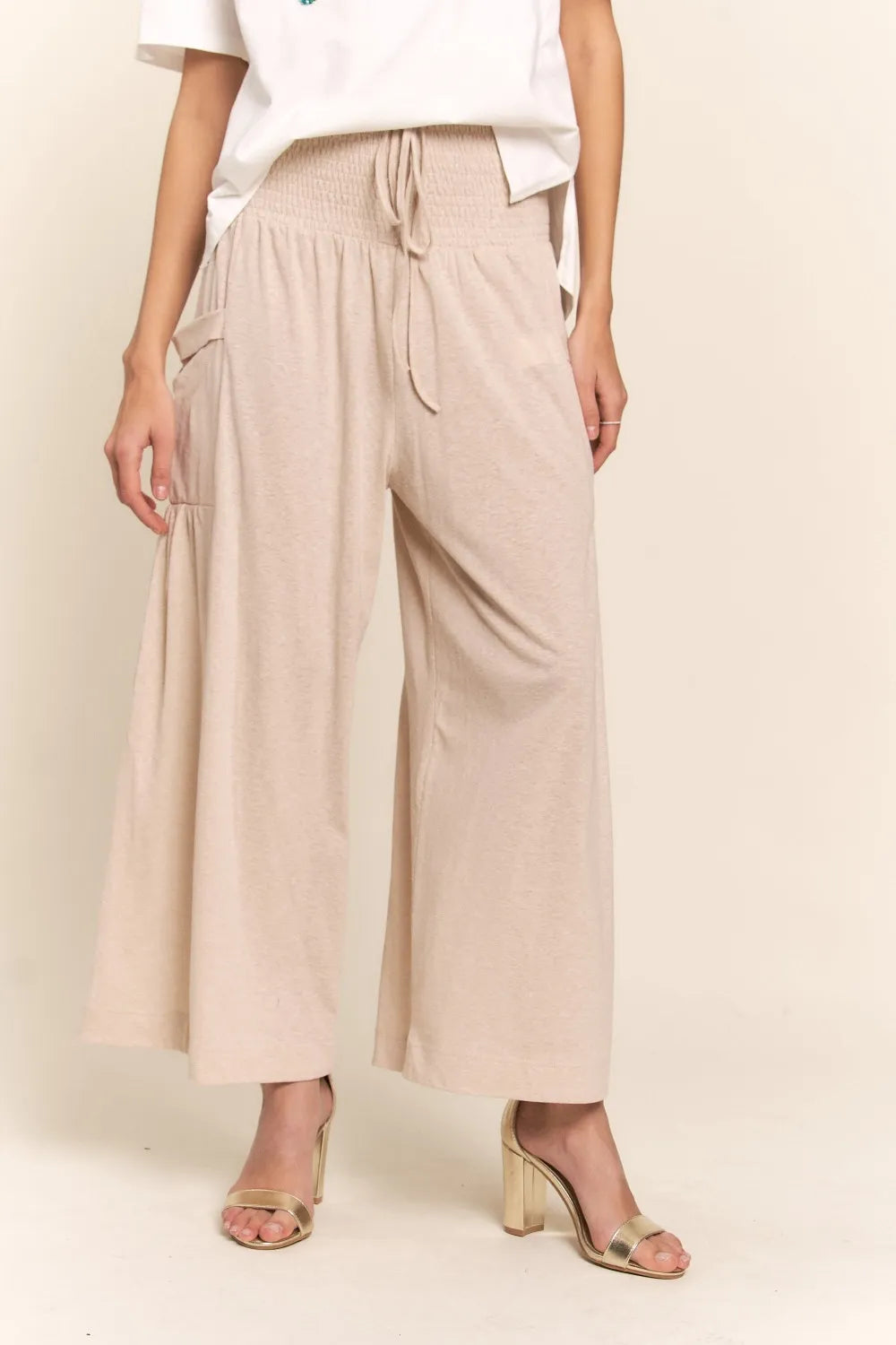 Light beige wide-leg pants with smocked waist, drawstring tie, and pockets