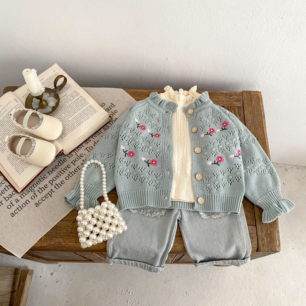 Blue-gray embroidered knit cardigan with ruffle neckline, button front, and red floral motifs.