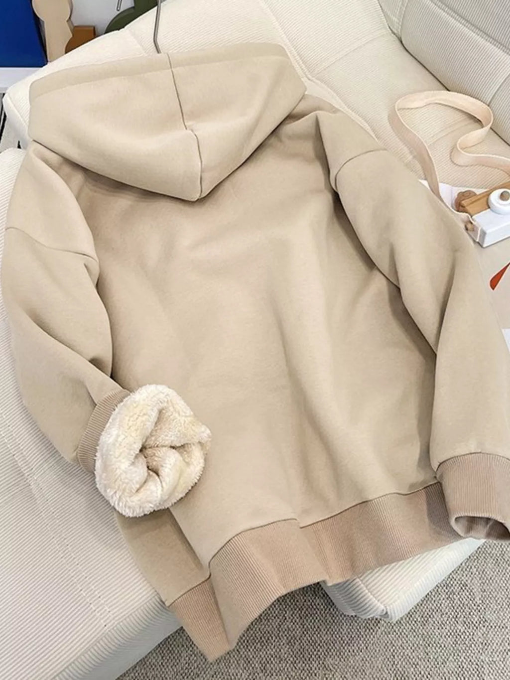 Apricot fleece-lined zip-up hoodie laid out: hood, zipper front, plush sherpa cuffs.