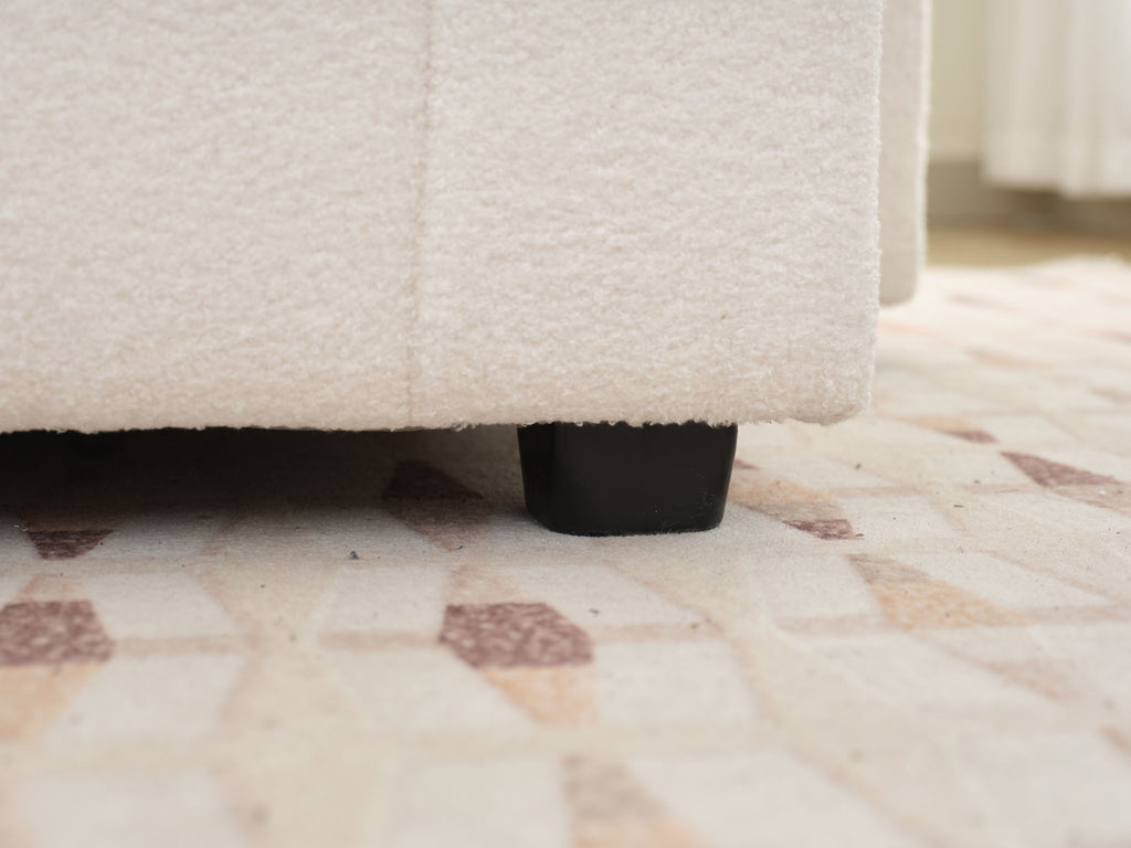 Beige sofa seat corner with black leg base detail beneath the frame.