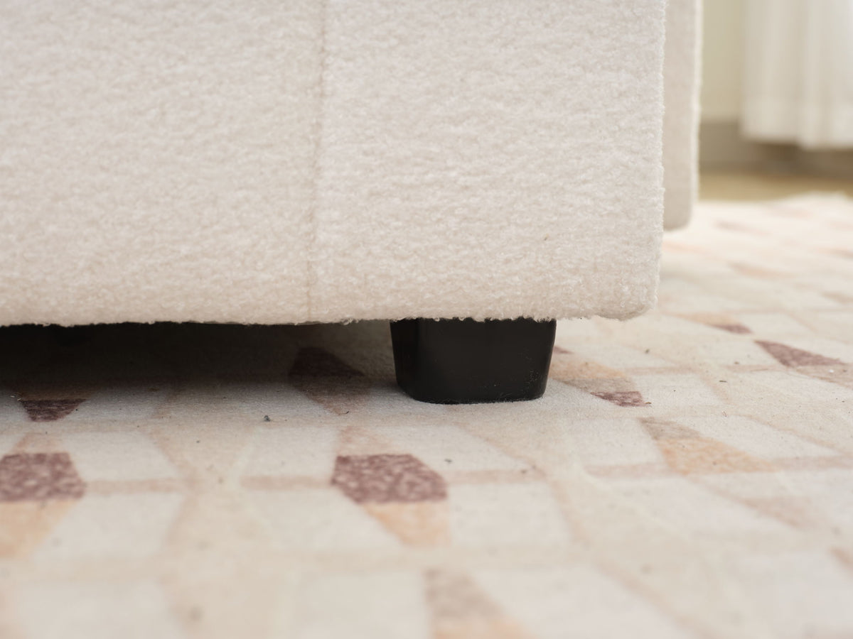 Beige sofa seat corner with black leg base detail beneath the frame.