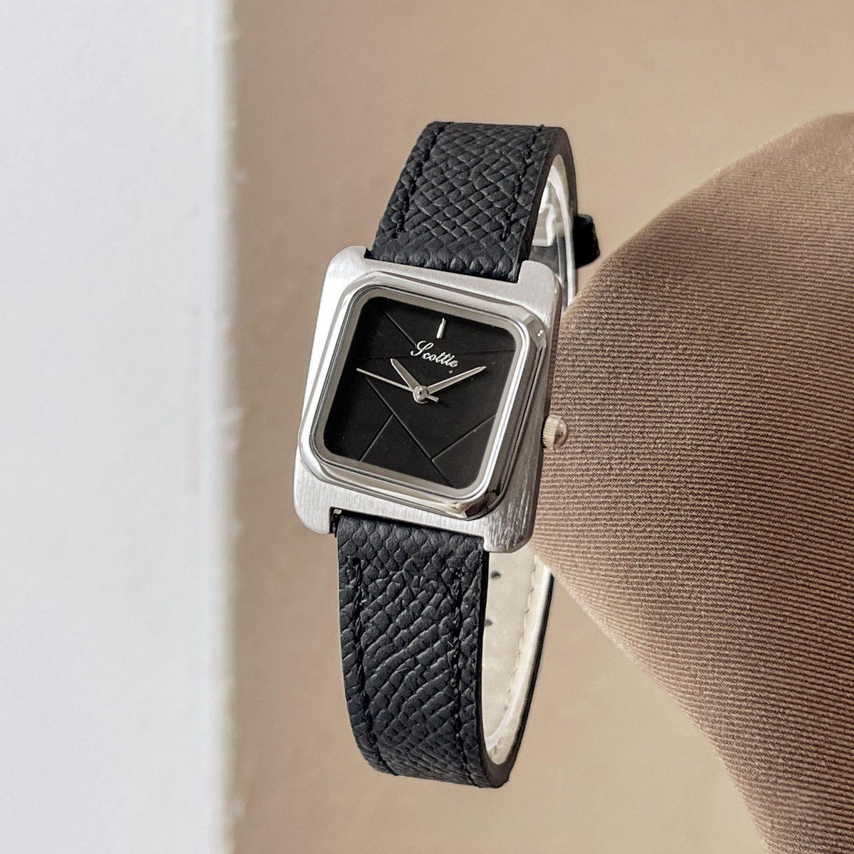 Square quartz watch with silver case, black leather strap, and black dial