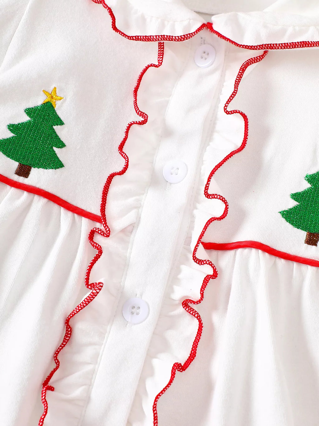 White dress front with green tree embroidery, red scalloped trim, and buttons