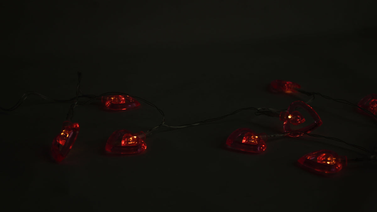 Red-glowing LED heart string lights with heart bulbs on a wire strand