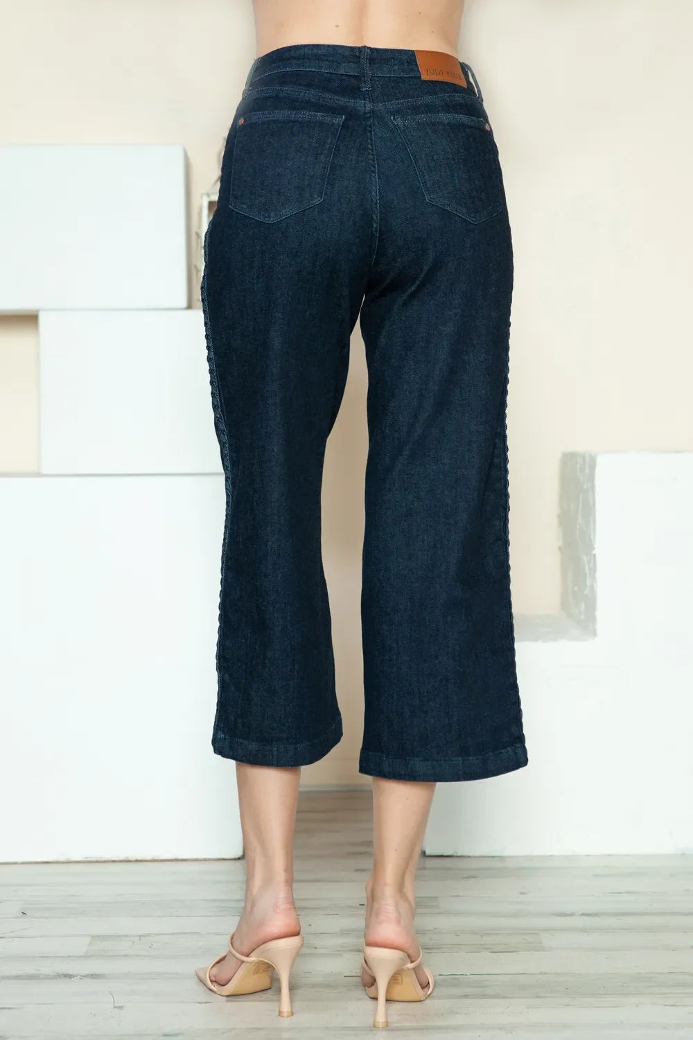 Back view of dark blue denim crop wide-leg jeans, mid-rise with stitched seams.