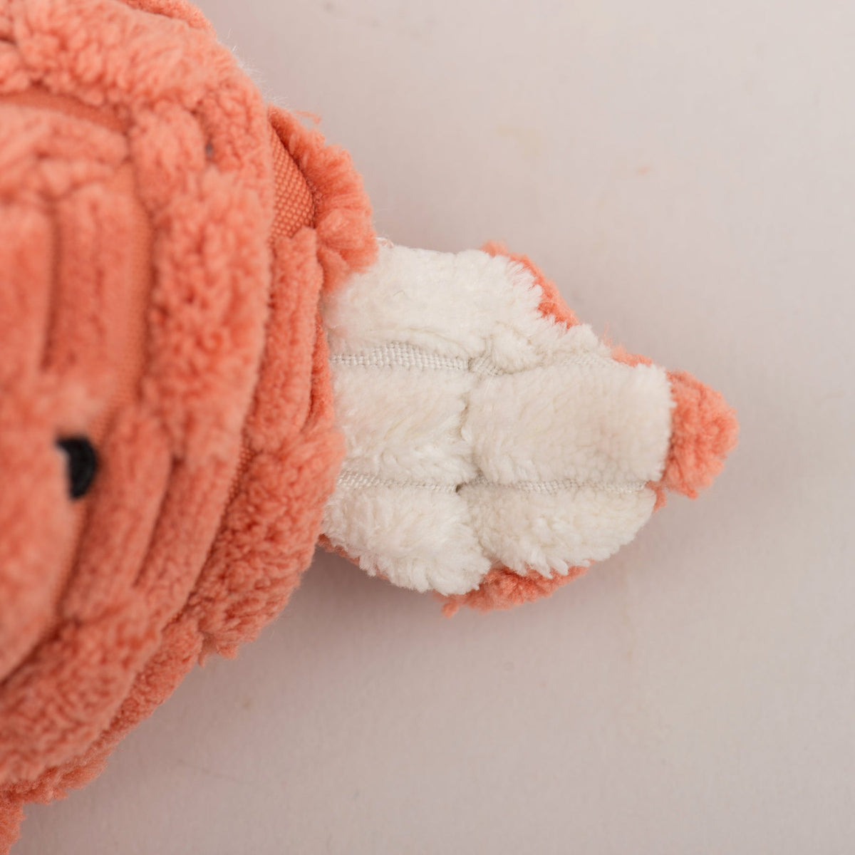 Close-up of rust plush toy arm and paw with white lining