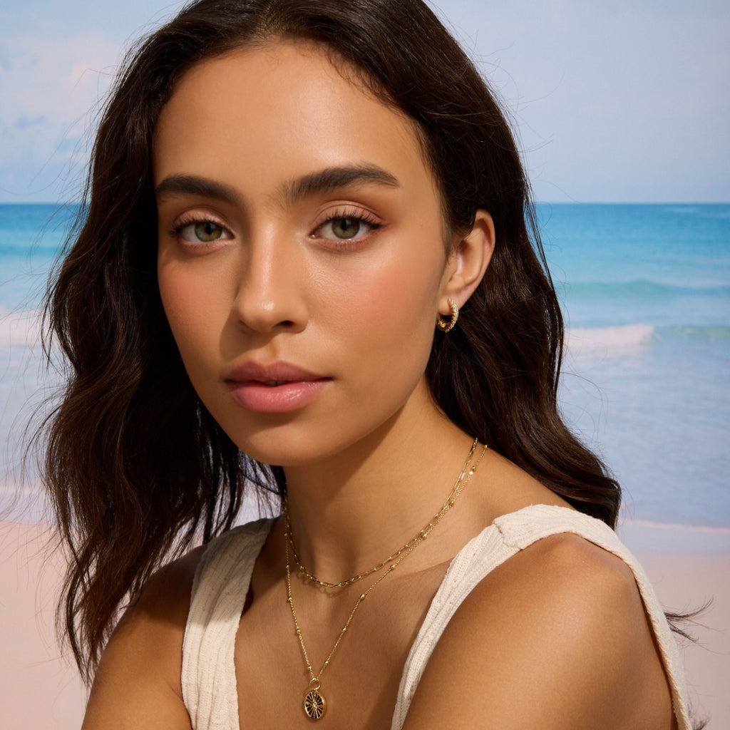 Gold double pavé hoop earrings on a woman wearing a cream top