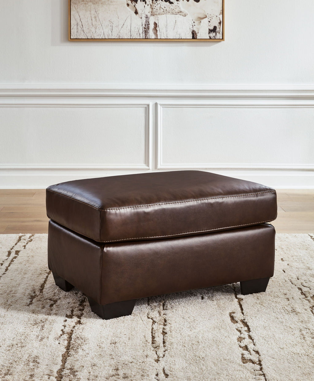 Dark brown padded ottoman with stitched top and black square tapered legs