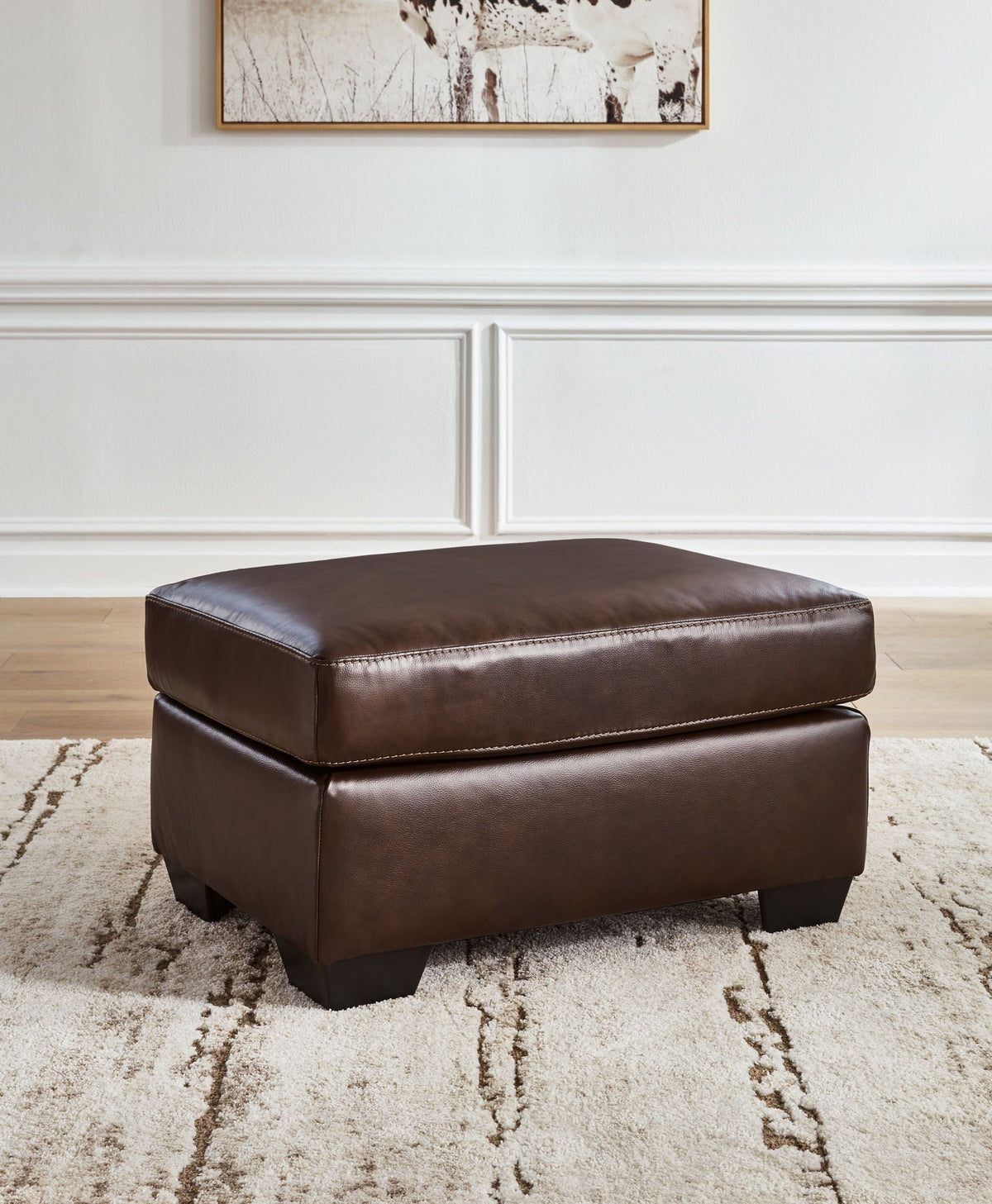 Dark brown padded ottoman with stitched top and black square tapered legs