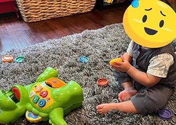Green counting dinosaur toy on carpet with loose food disks near a child