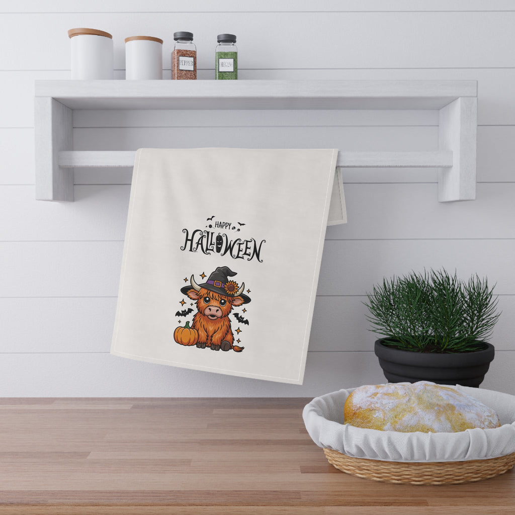 White Halloween tea towel on open shelf, featuring highland cow graphic and “Happy Halloween”