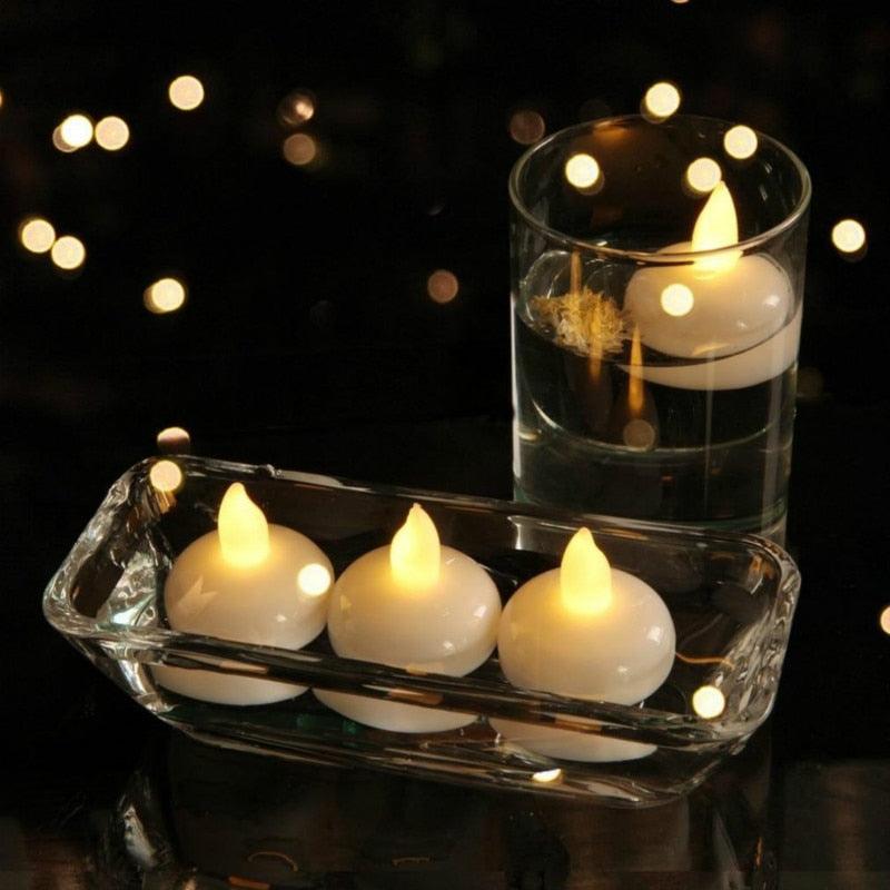 Floating LED tea light candles with warm yellow glow in a clear water dish