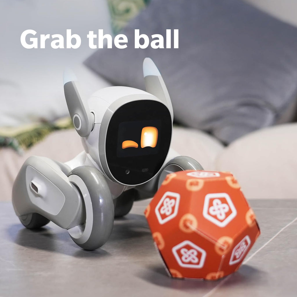 White robotic dog reaching toward an orange ball on a couch