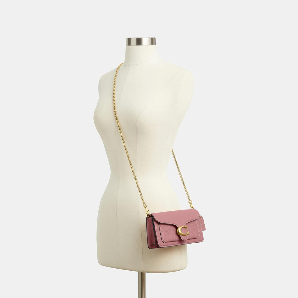Rose pebbled leather crossbody bag on model with gold chain and Tabby C clasp