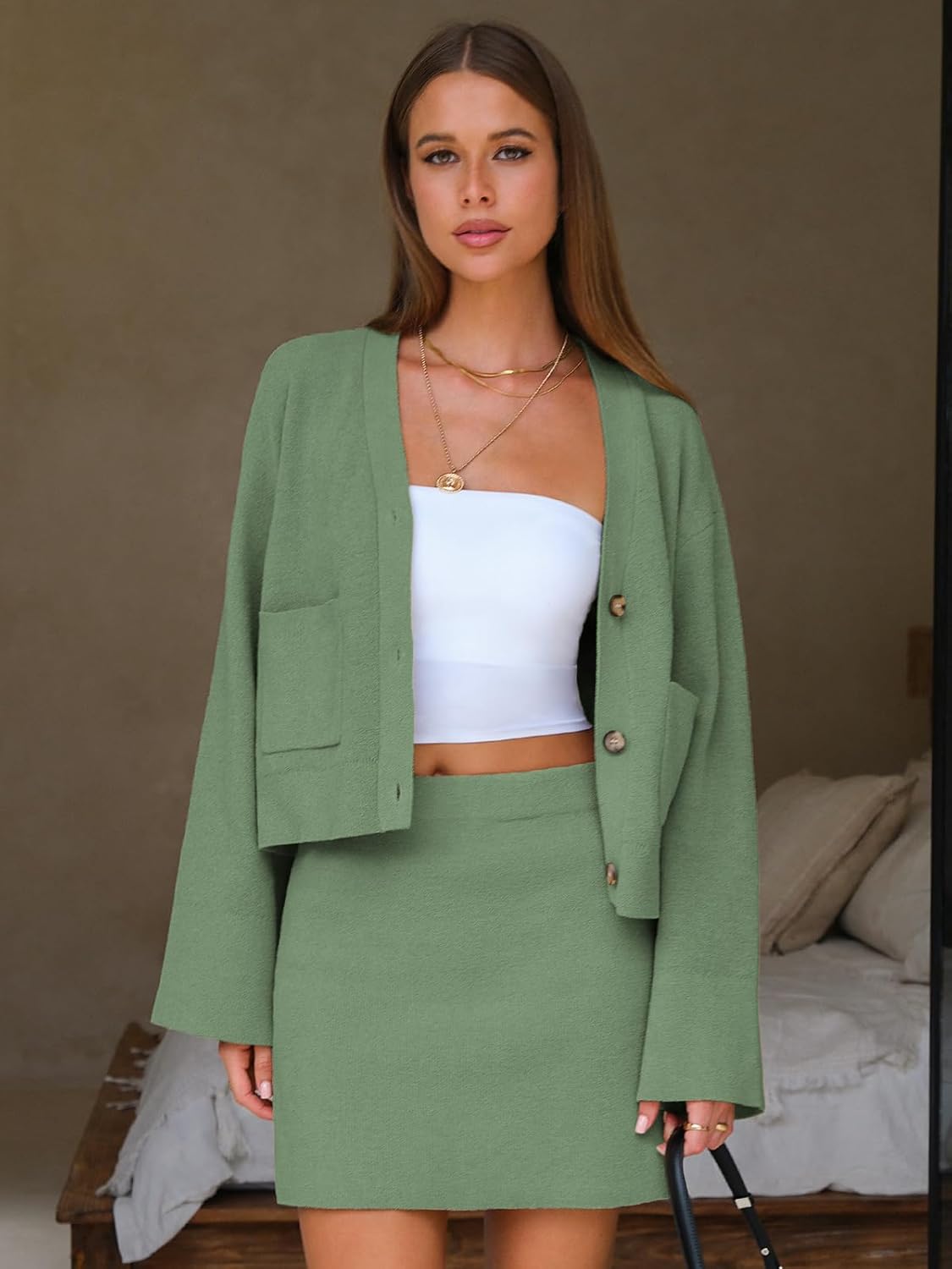 Light green knit cardigan with buttons over mini skirt, worn with a white camisole