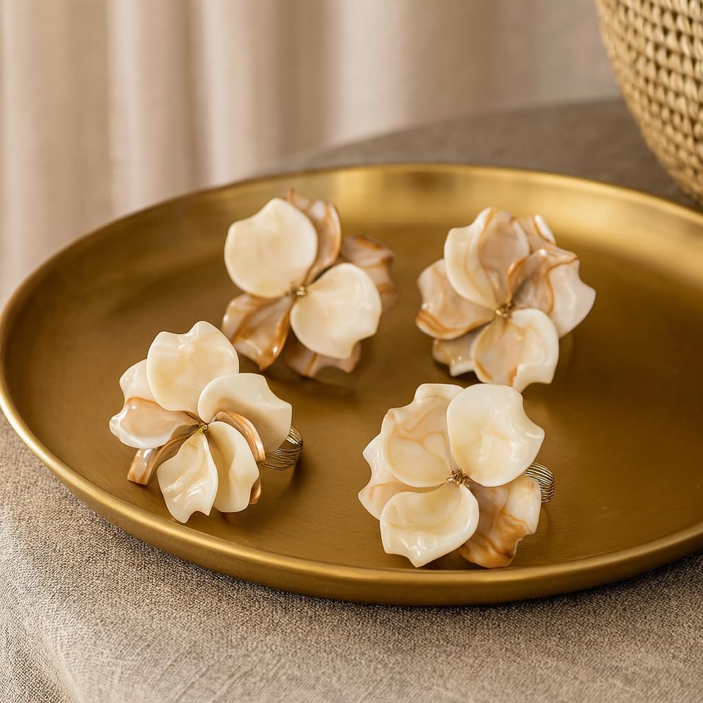 Set of four cream flower napkin rings with silver loops on a gold tray