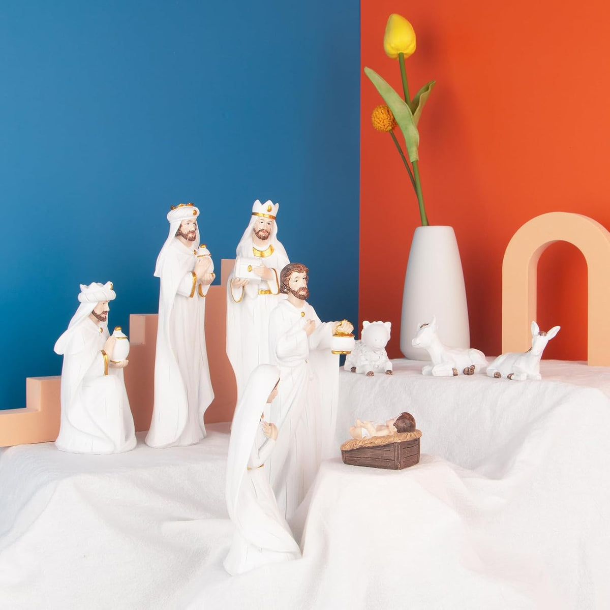 White resin nativity set on a platform with standing figures, baby, and lambs
