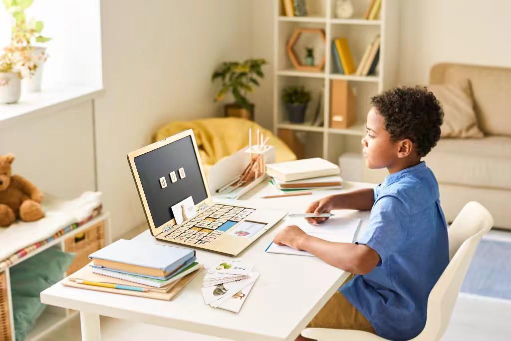 Child using wooden learning laptop on a desk with learning cards