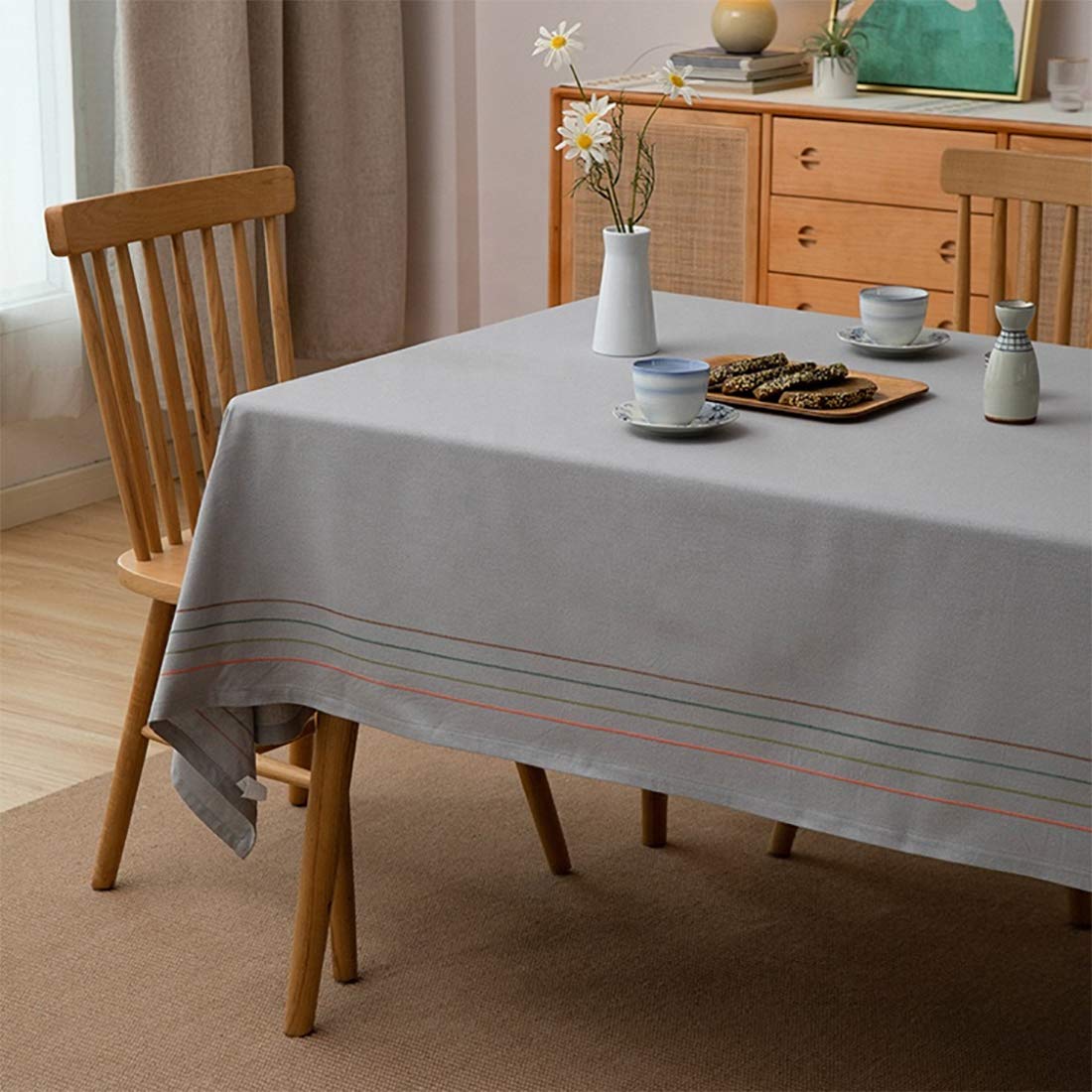 Cotton tablecloth with striped border and tassel trim, light grey fabric with color bands.