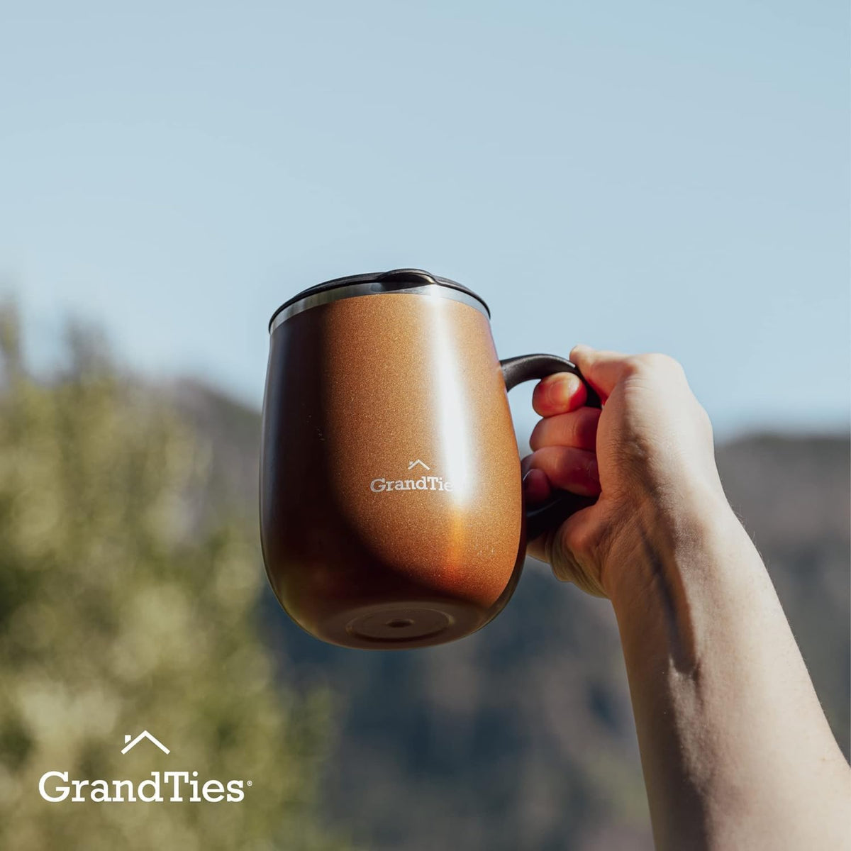 Cognac metallic insulated coffee mug with handle, held in a hand